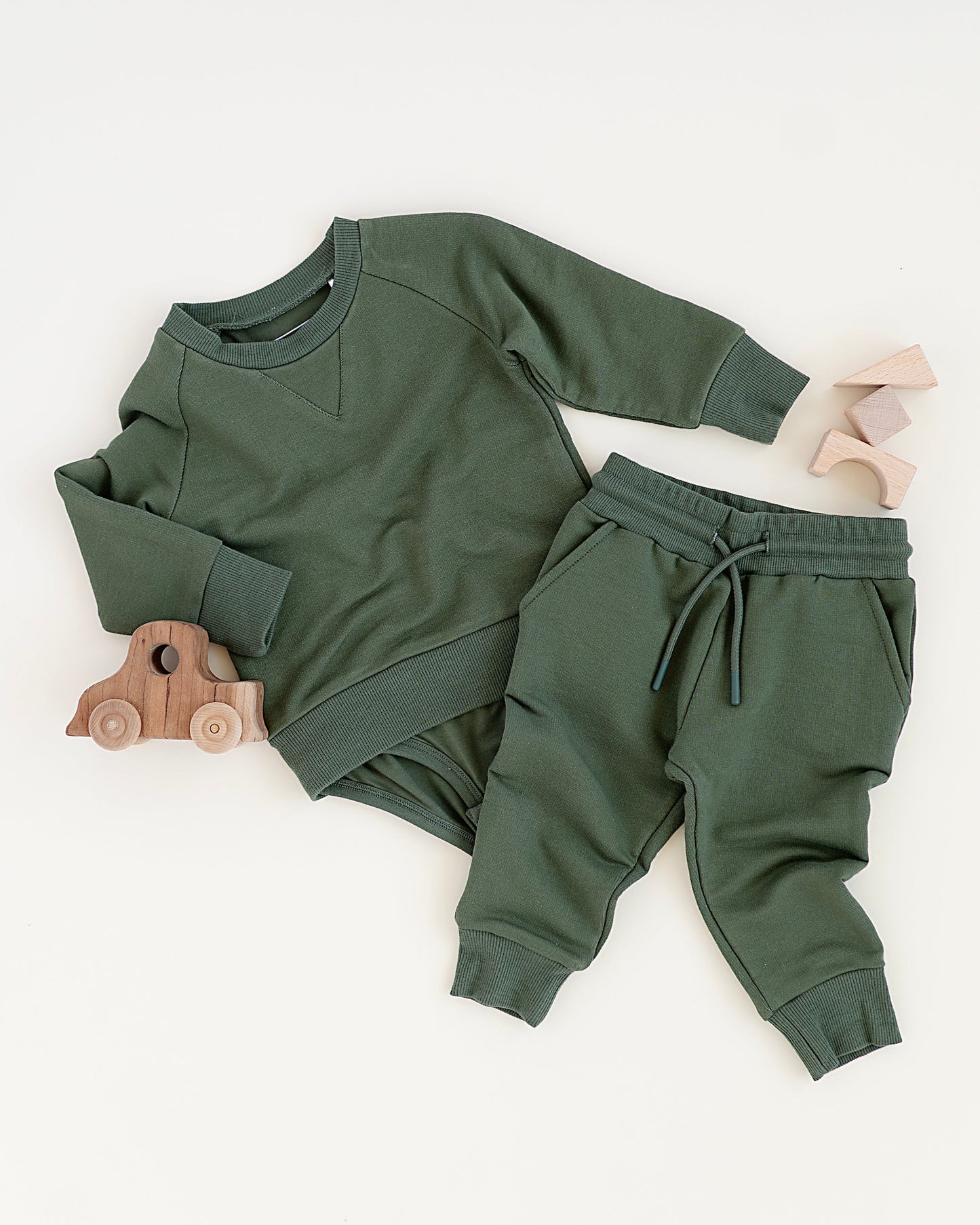 Green baby sweatshirt onesie + sweatpant outfit on a white background