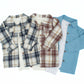 Two baby boy flannel shirts attached to a bamboo baby onesie and a denim blue overshirt with an attached white bamboo onesie on a white background