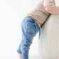 Baby wearing blue pants and a beige shirt on a white background