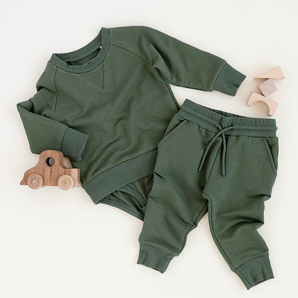 Green baby sweatshirt onesie + sweatpant outfit on a white background