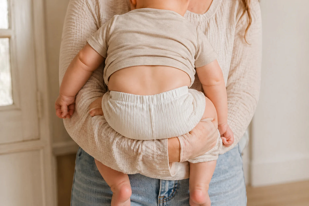 Neutral baby clothes hanging in a soft nursery