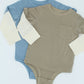 Two baby rompers, one blue and one beige, on a light blue background.
